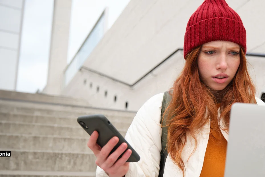 Donna preoccupata che consulta smartphone e computer su una scalinata a Milano, metafora della raccolta prove digitali e screenshot WhatsApp per processi di stalking e atti persecutori – Studio Legale Alessandro Salonia