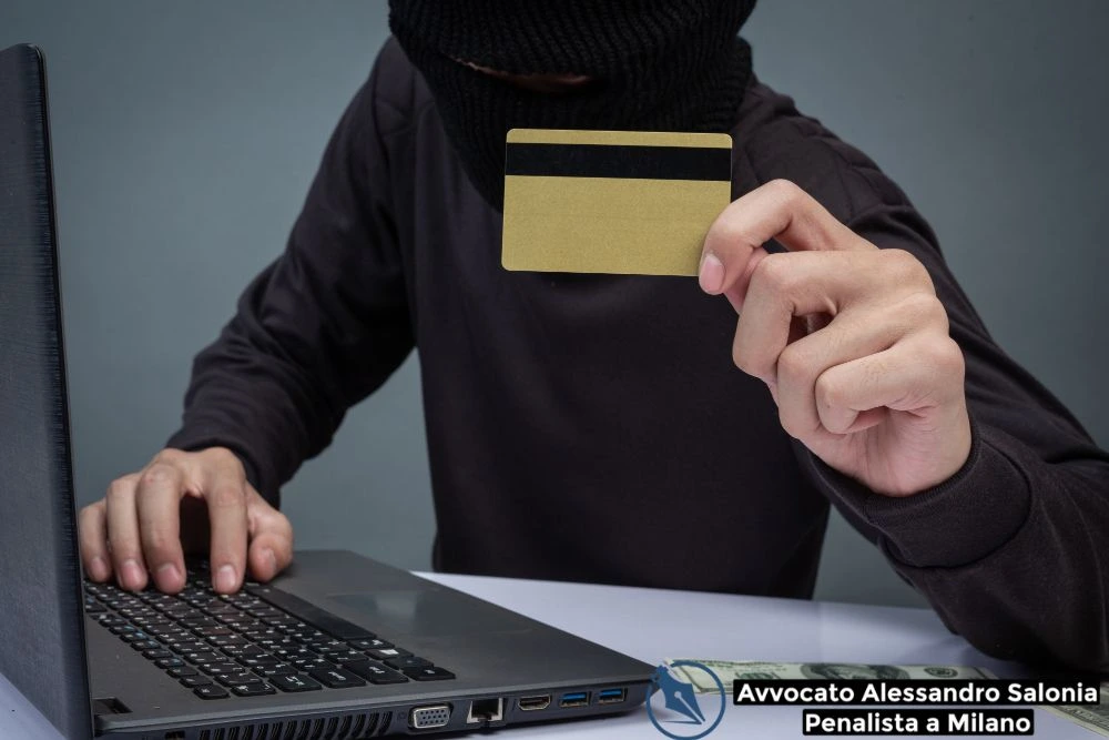 Soggetto incappucciato al computer con carta di credito, rappresentazione di truffa online minorata difesa. Affidati a un esperto Avvocato penalista Milano per la tutela legale nei reati informatici.